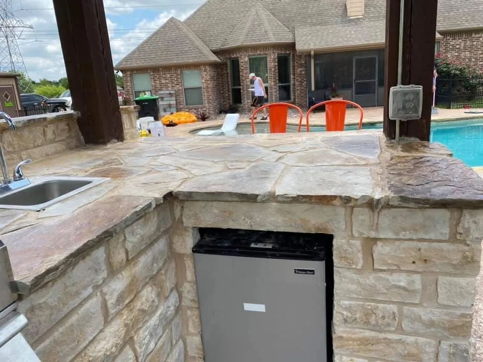 outdoor kitchen area with sink, mini fridge, and weather resistant outlet cover